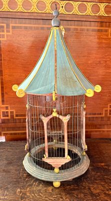 une cage à oiseaux posée sur une table, avec un oiseau à l'intérieur