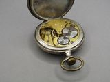 a silver pocket watch with a gold case on a table
