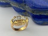 une image représentant une bague en or sertie de diamants, posée sur une pierre bleue