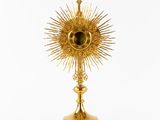 une image représentant une statue dorée du soleil sur laquelle figure une croix