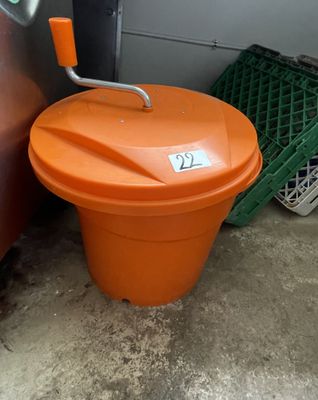 an orange trash can sitting next to a red car
