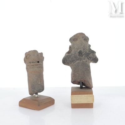 deux figurines en pierre représentant un homme et une femme, posées sur un socle en bois