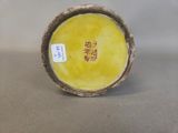 a yellow vase sitting on a table with chinese writing on it