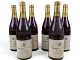 six bouteilles de vin posées les unes à côté des autres sur une surface blanche