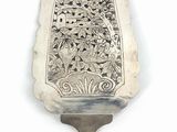 a silver spoon with a design on it on a white surface