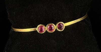 a close up of a gold belt with three ruby stones