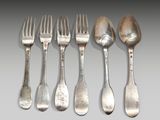 six forks and spoons are lined up on a gray surface