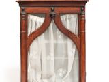 une vieille vitrine en bois surmontée d'un rideau