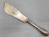un vieux couteau d'argenterie à long manche posé sur une surface grise
