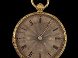 a gold pocket watch with roman numerals on the face