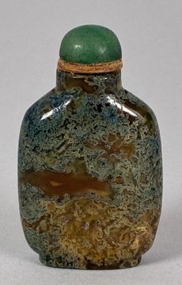 a green and brown vase with a lid on a white surface