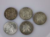 six types différents de pièces d'argent sur une surface blanche