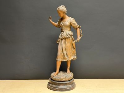 statue d'une femme tenant un oiseau, posée sur un socle