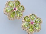 paire de boucles d'oreilles en forme de fleur, composées de péridot et de diamants, sur un fond blanc
