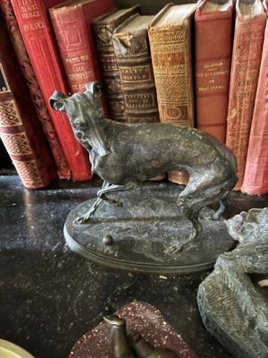 une statue représentant un chien assis au sommet d'une bibliothèque