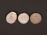 three silver coins sitting on top of a black surface