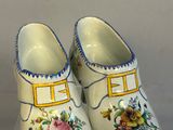 a pair of clogs with flowers on them on a clear surface