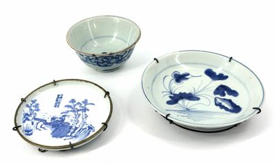 three blue and white plates and a bowl on a white surface