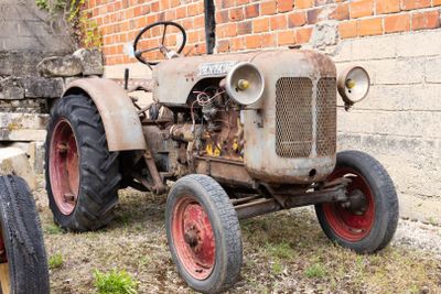 un vieux tracteur garé devant un mur de briques