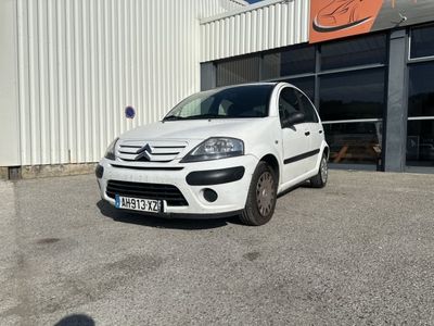 la petite voiture blanche est garée devant un bâtiment