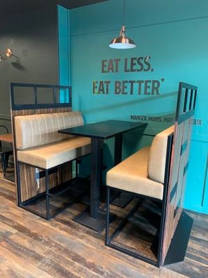 un stand avec deux chaises et une table, sur laquelle est posée une pancarte indiquant « Mangez moins, mangez mieux »