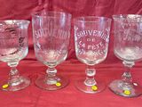 four wine glasses are lined up on a red table cloth