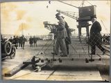 a black and white photo of a group of men standing on a boat