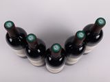 six bottles of wine lined up in a row on a white surface