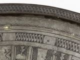 a close up of a silver plate with designs on it