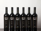 six bottles of wine are lined up on a wooden table