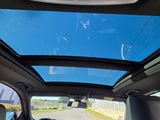 the interior of a car with the sunroof down and the driver ' s hand on the steering wheel