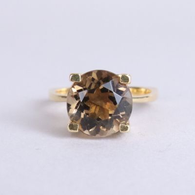 un gros plan d'une bague ornée d'un diamant brun sur un fond blanc