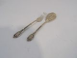 two forks and a spoon on a white surface