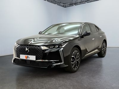 Une voiture noire est garée dans une grande pièce aux murs blancs.