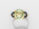 un gros plan d'une bague ornée d'une pierre verte entourée de saphirs bleus