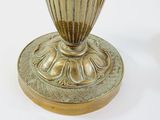 a gold vase with a flower on it on a white surface