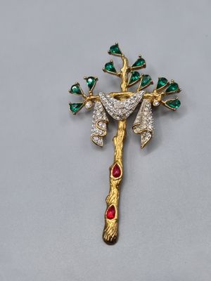 une image représentant une croix en or ornée de pierres vertes et rouges