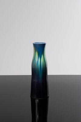 un vase bleu et vert posé sur une table noire