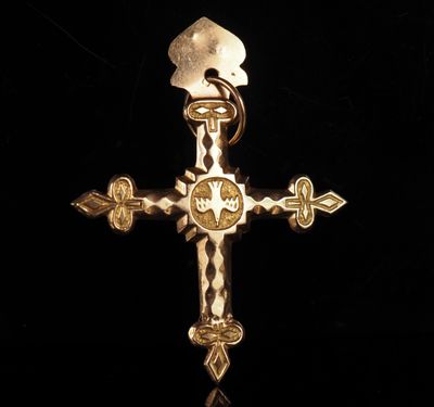 un gros plan d'une croix en or sur laquelle figure une flèche