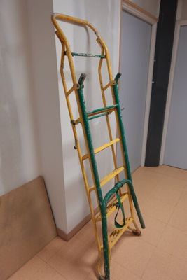 une échelle jaune et verte appuyée contre un mur blanc dans une pièce