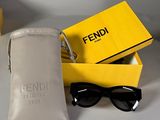 des lunettes de soleil Fendi dans un étui et une paire de lunettes de soleil posée sur une table