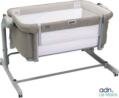 the baby crib is sitting on a metal stand with a white cover