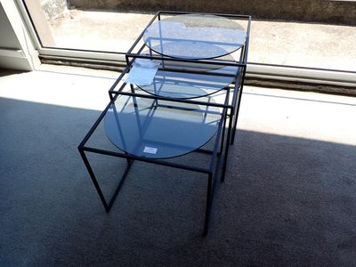une table en verre avec un plateau en verre, placée devant une fenêtre