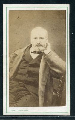 une vieille photo d'un homme assis sur une chaise, la main posée sur le menton