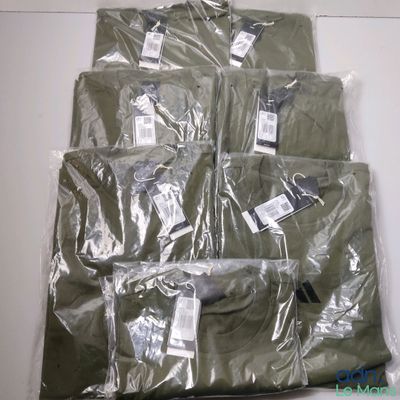 une pile de t-shirts verts emballés dans du plastique, posée sur une table