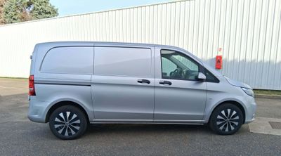 La camionnette argentée est garée devant un immeuble blanc.
