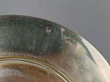a silver plate on a table with a gray background