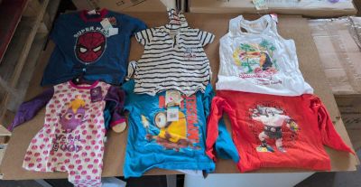de nombreux vêtements d'enfants posés sur une table dans une pièce