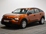 La voiture orange est garée sur un sol à damier, dans une pièce.