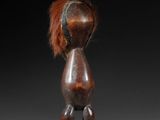 a close up of a wooden figure with a red hair